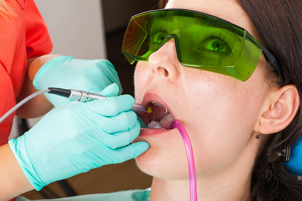 Dentist using a professional dental laser for oral treatment
